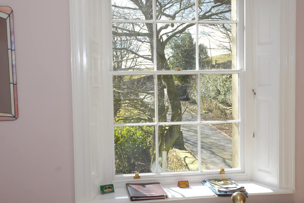 A window with a view of trees and a path outside.