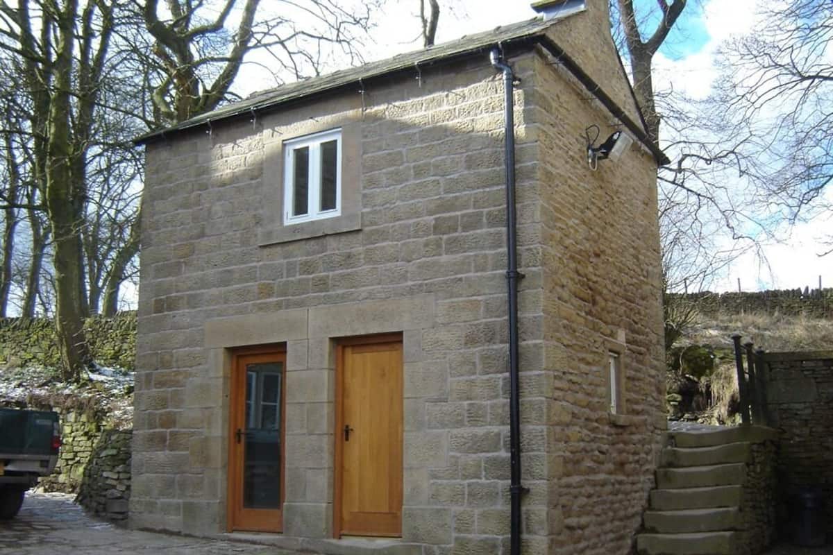 A stone building with two wooden doors and a window.