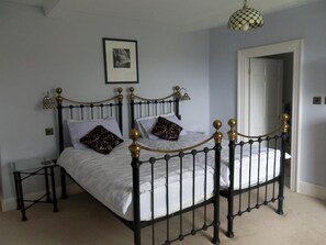 A four-poster bed with a black frame and gold accents, a bedside table, and a framed picture on the wall. - Rushop Hall (Buxton)
