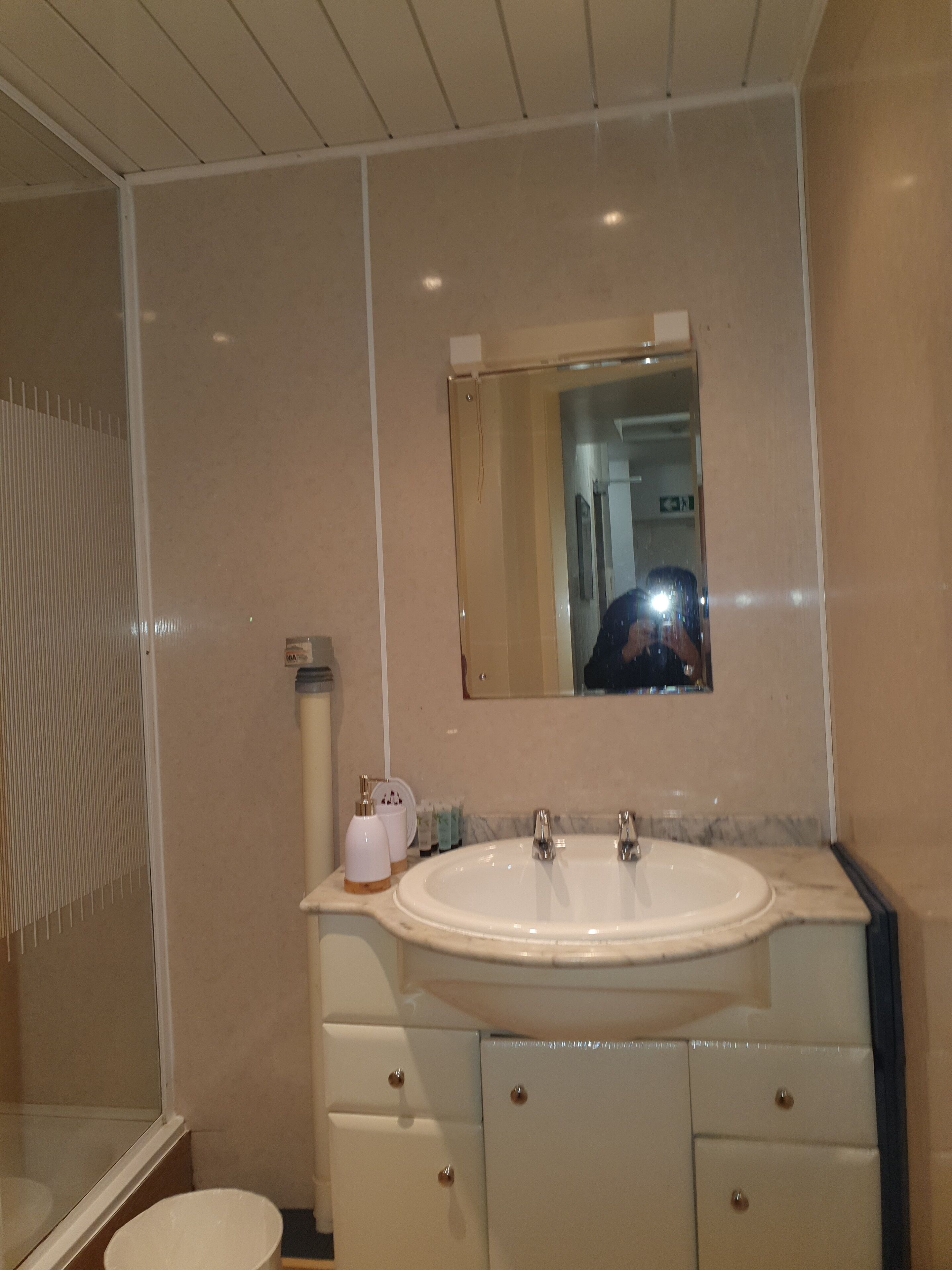 A bathroom with a large sink, mirror, and two drawers.