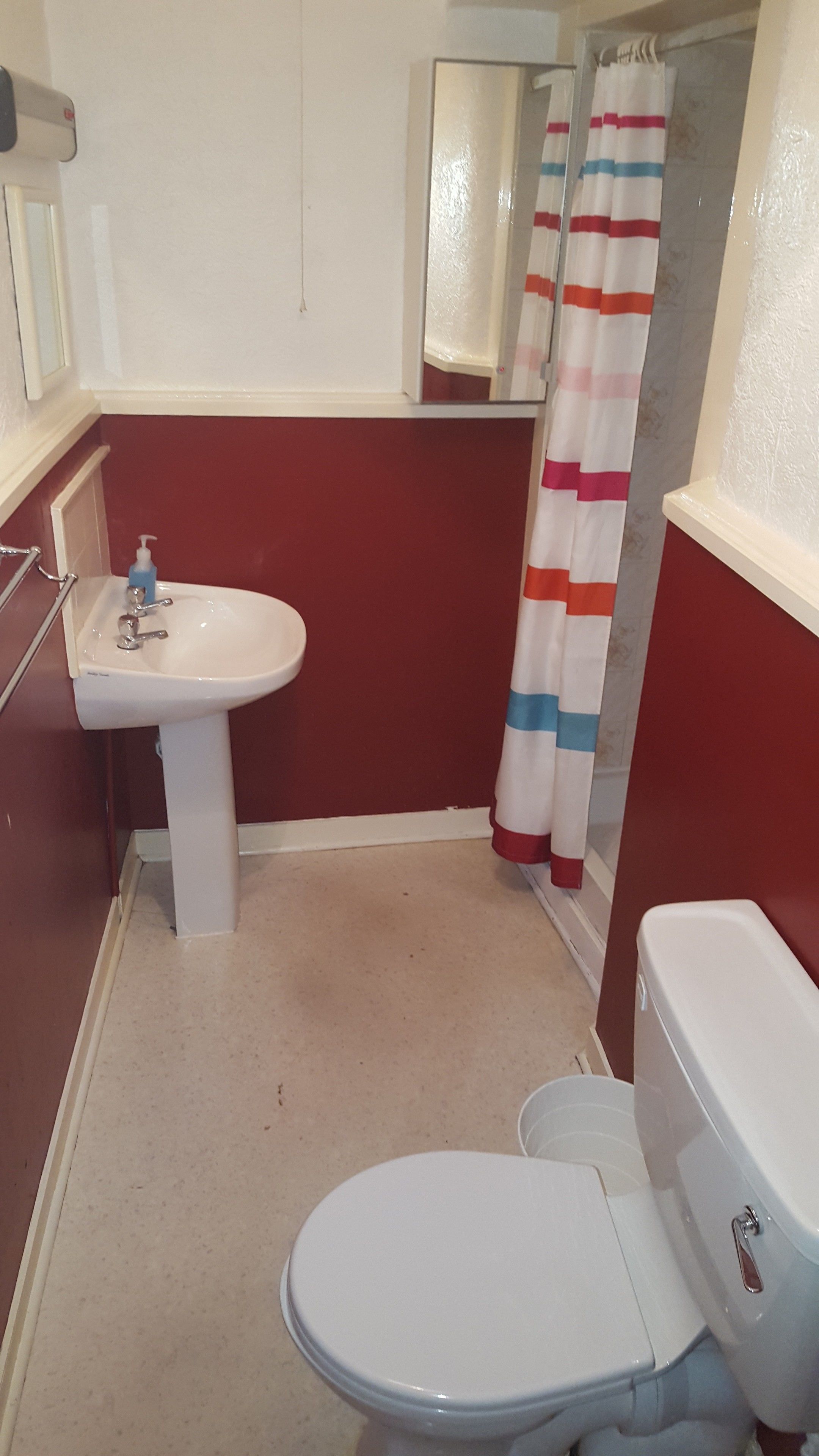 Un baño con lavamanos blanco, inodoro y cortina de ducha.