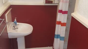 Un baño con lavamanos blanco, inodoro y cortina de ducha.