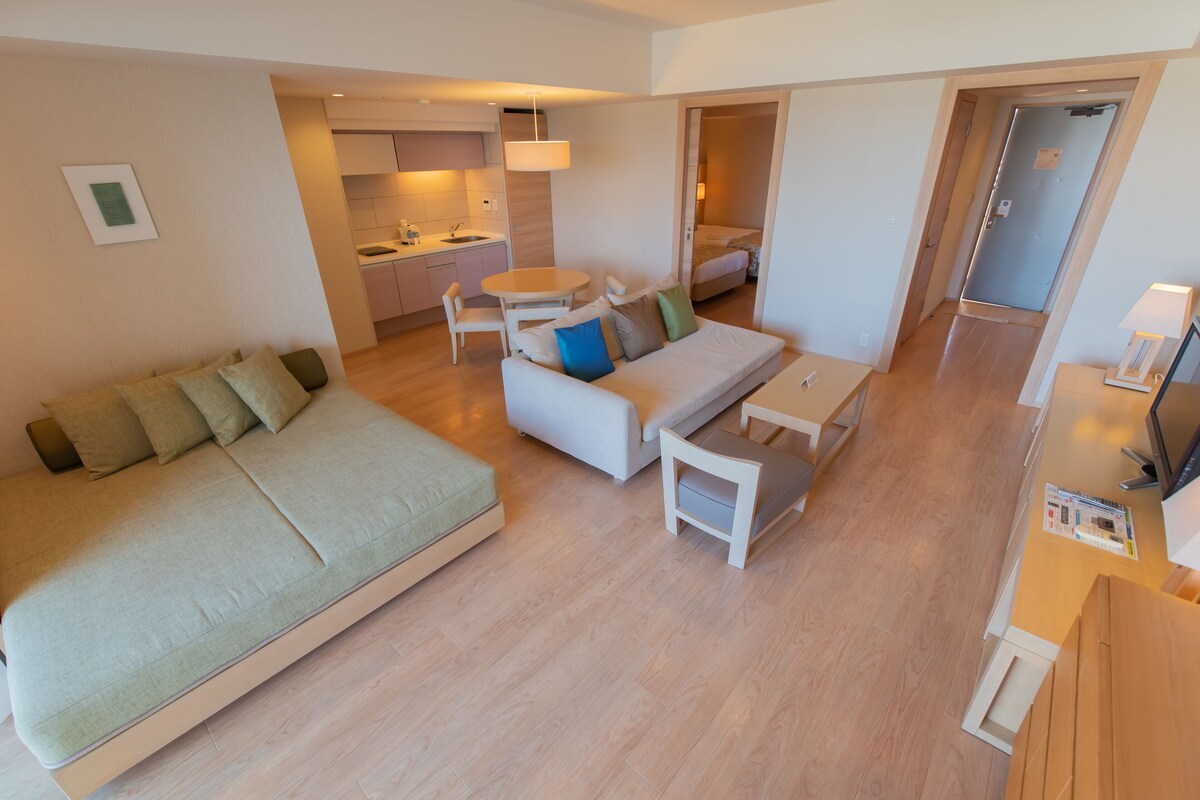 Un apartamento moderno con una cama grande, un sofá, una mesa de comedor y una zona de cocina.