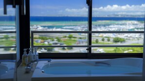 Un baño con un amplio ventanal que ofrece vistas a una ciudad costera.