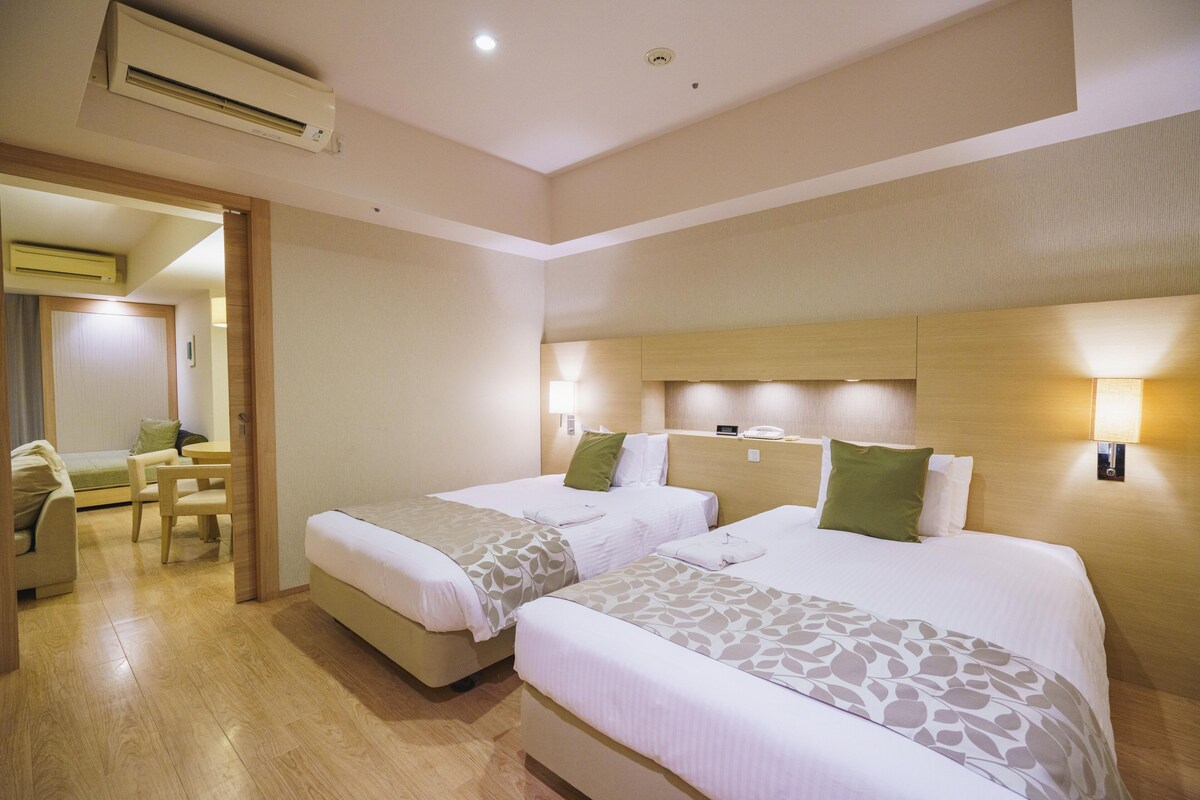 Habitación de hotel con dos camas, un escritorio y una silla.