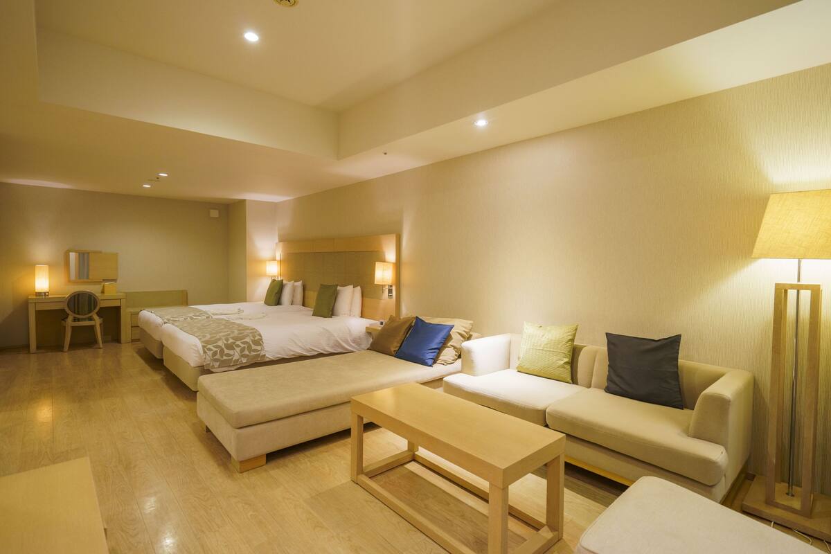 Una habitación de hotel con una cama, dos sofás, un escritorio y una silla.