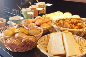 Una exhibición de productos horneados varios, incluyendo pan, croissants y bollos, en cestas de mimbre.