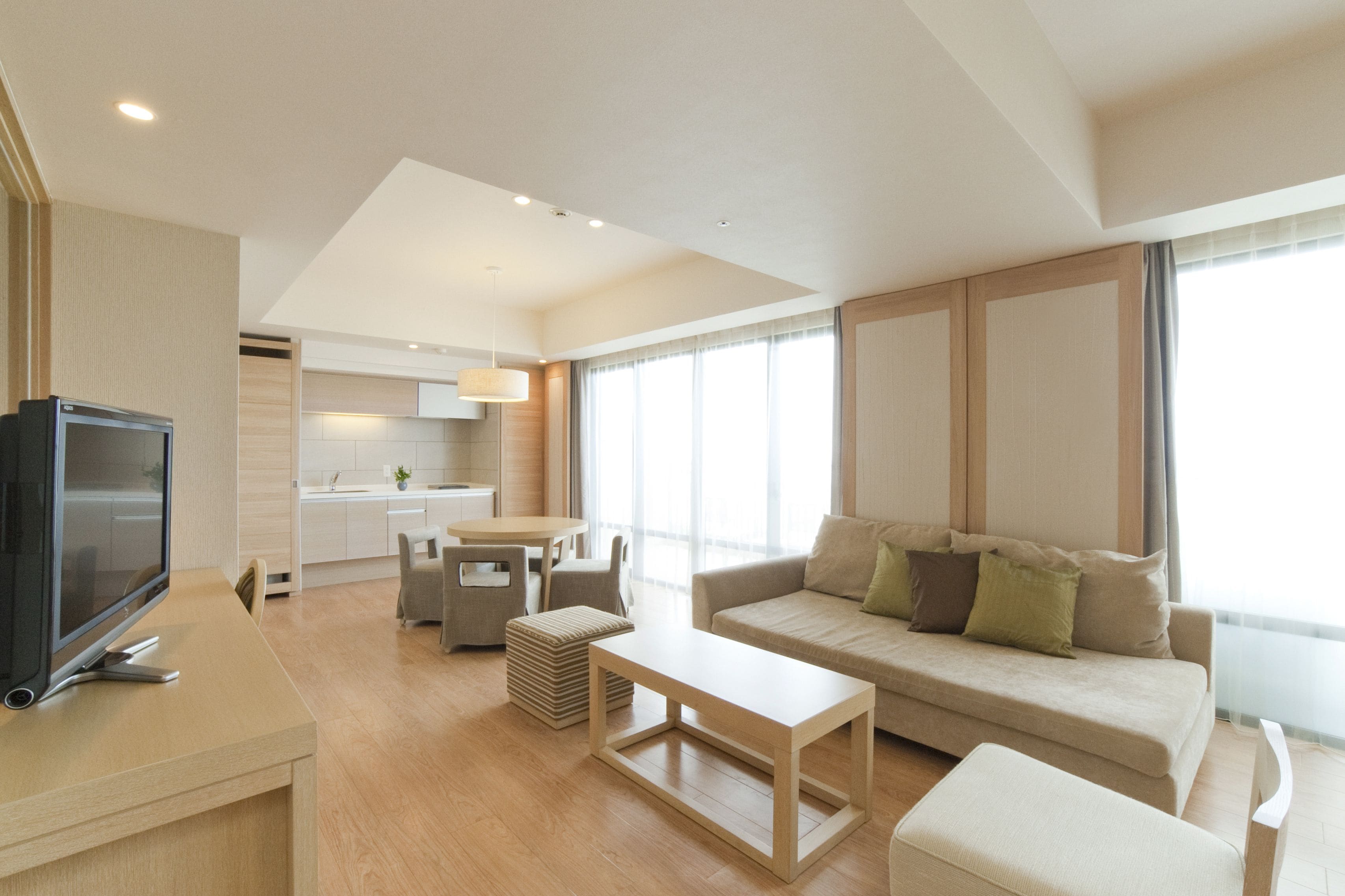 Una sala de estar moderna con una televisión de pantalla plana, un sofá, una mesa de centro y una zona de comedor con mesa y sillas.
