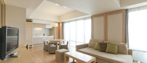 A modern living room with a flat-screen TV, a sofa, a coffee table, and a dining area with a table and chairs.