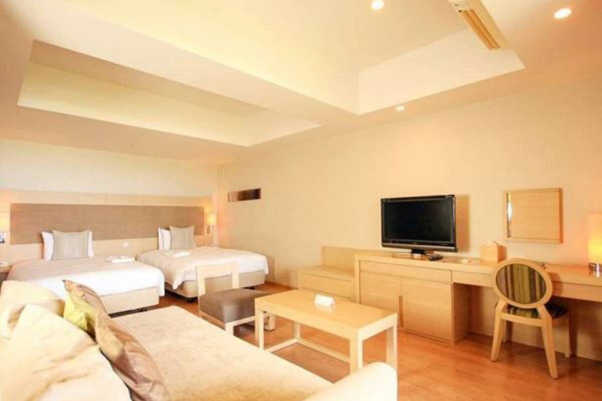 Una habitación de hotel con dos camas, un escritorio, un televisor y una silla.
