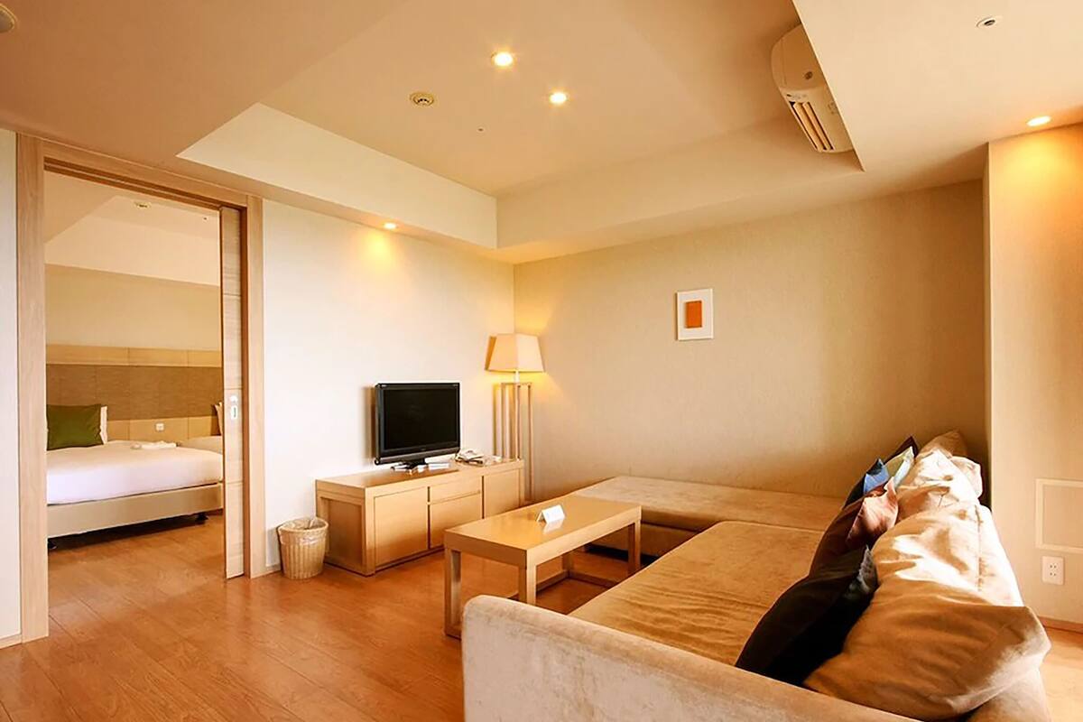 Una habitación de hotel moderna con cama, televisor, sofá y escritorio.