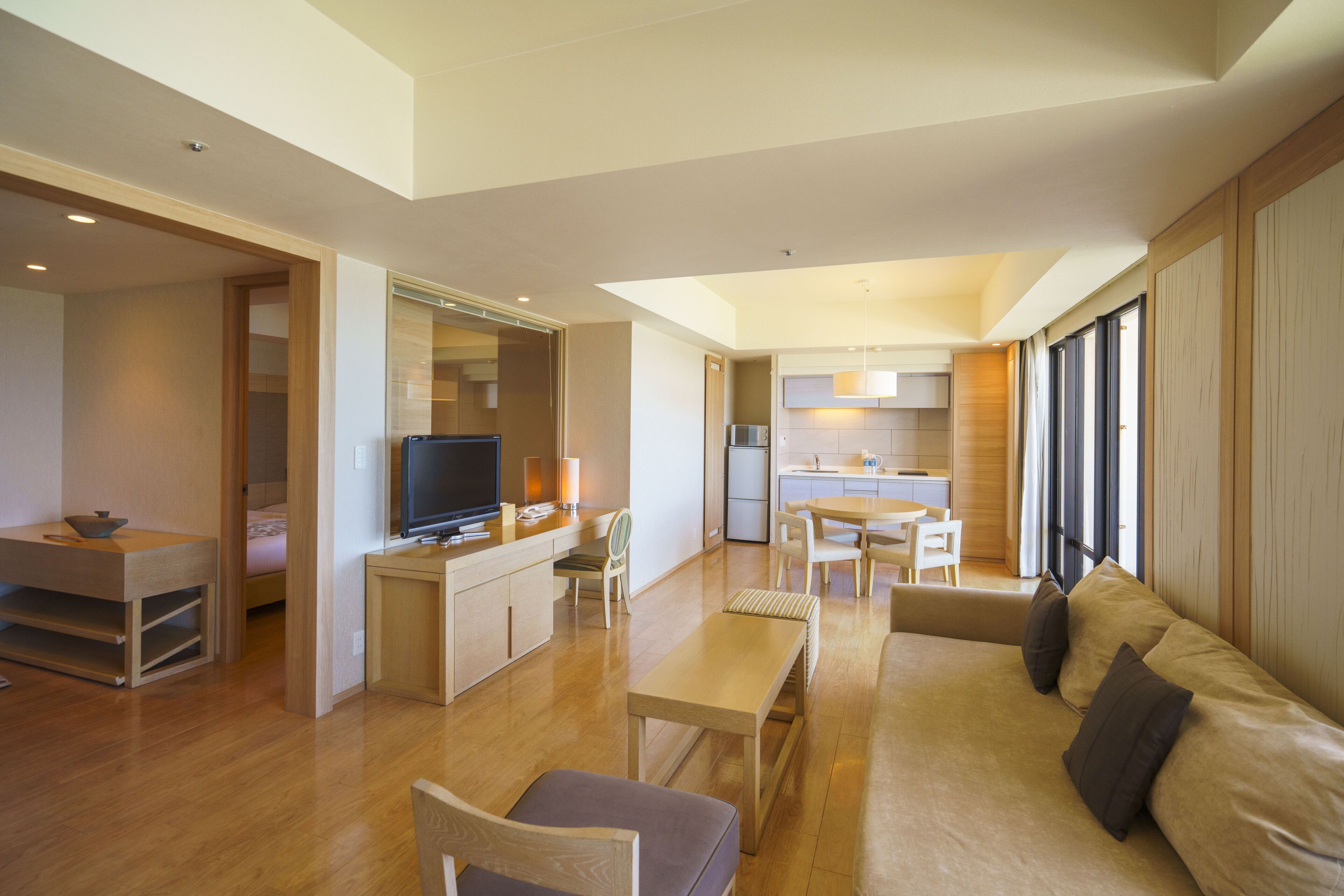 A modern living room with a sofa, a TV, and a dining area.