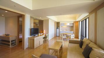 A modern living room with a sofa, a TV, and a dining area.