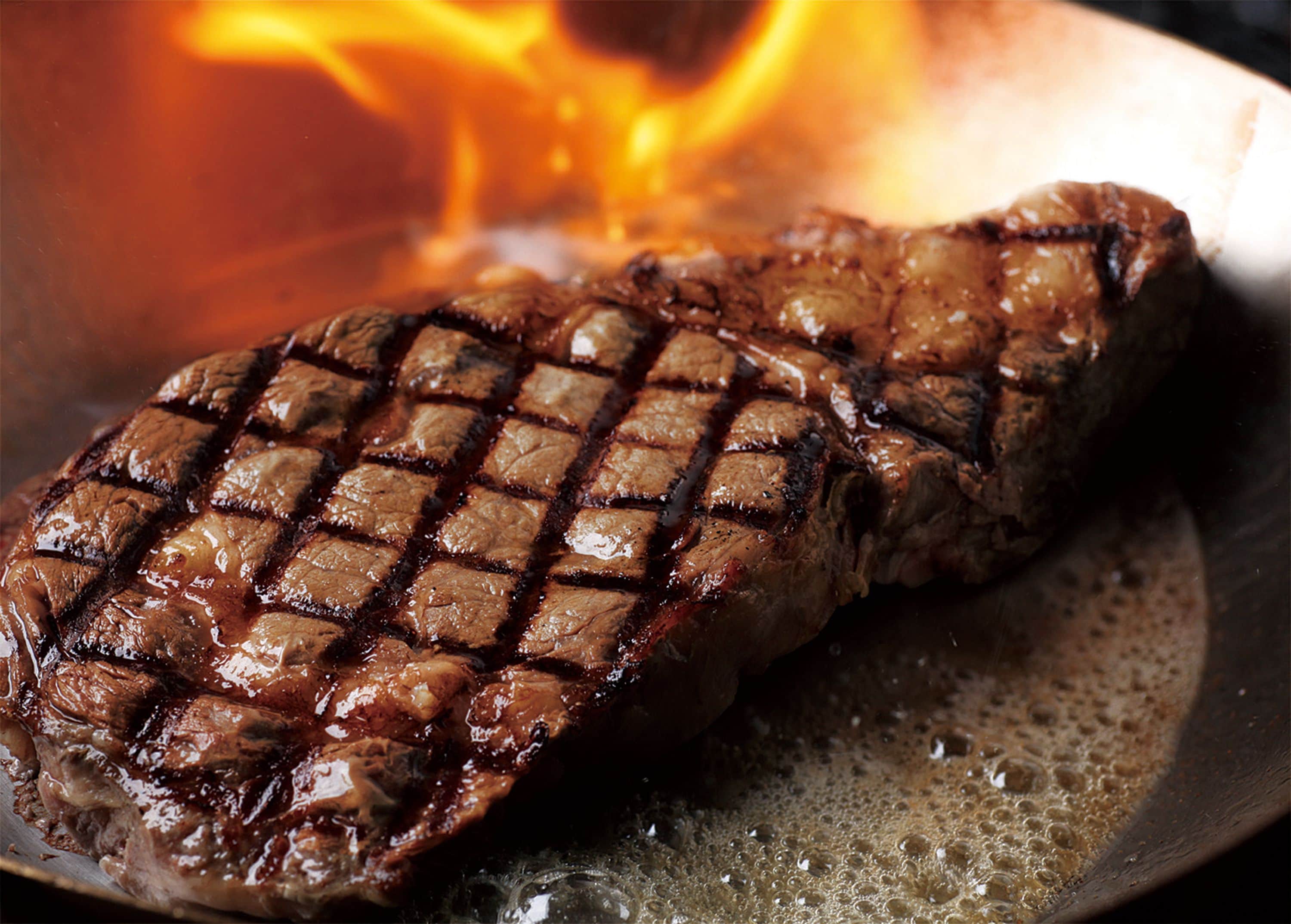 Bife grelhado com marcas de carvão na frigideira.