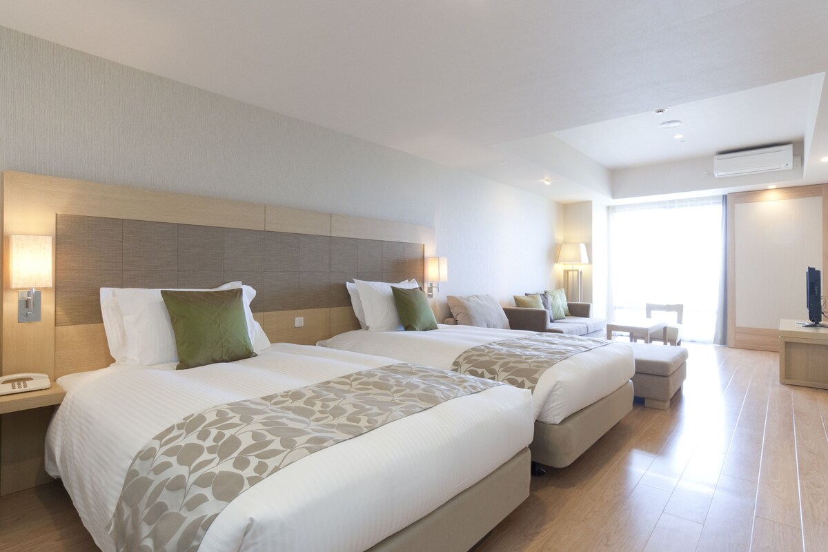 Una habitación de hotel con dos camas, un escritorio, una silla y un televisor.
