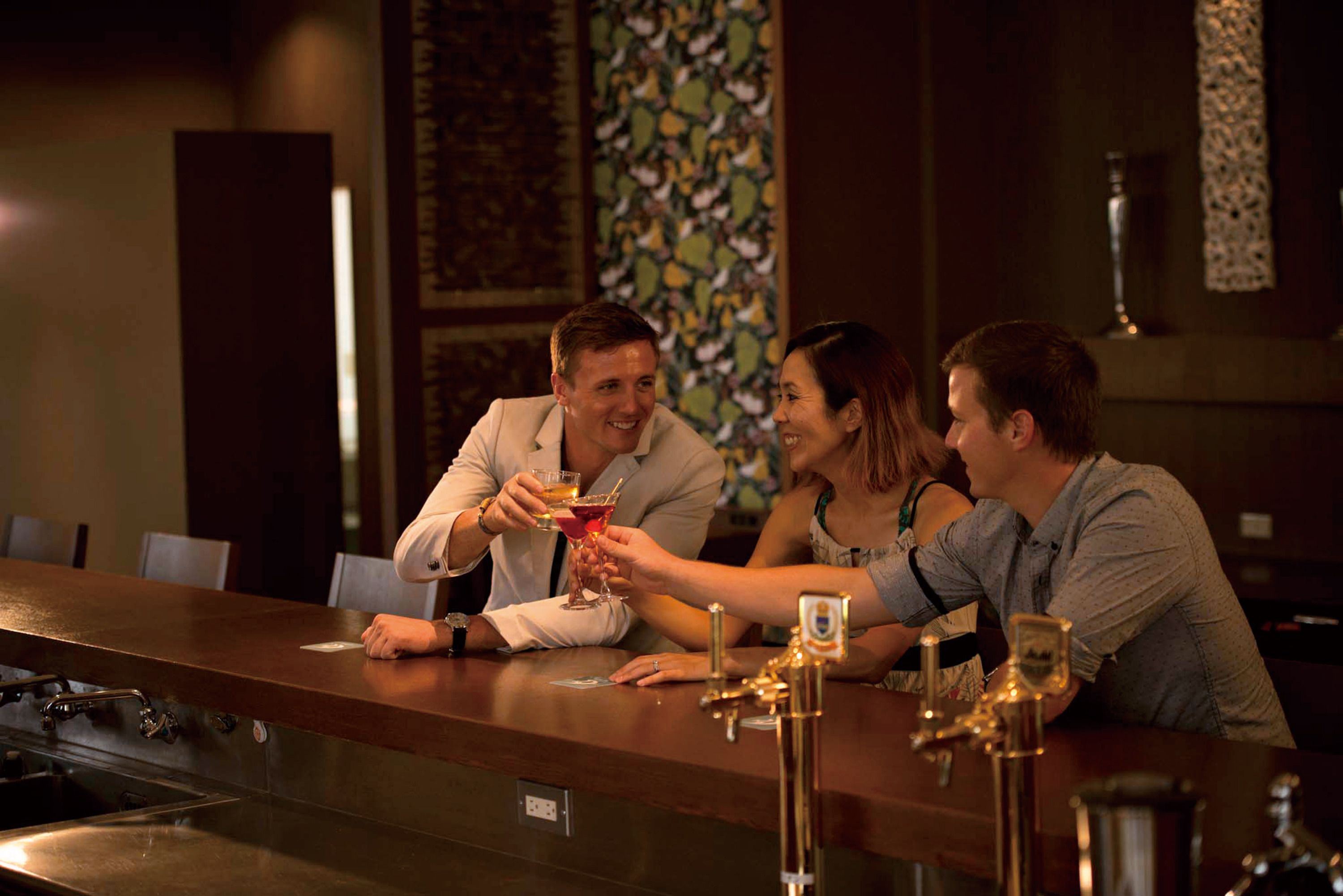 A bar area with a long counter, multiple taps, and a decorative wall in the background.