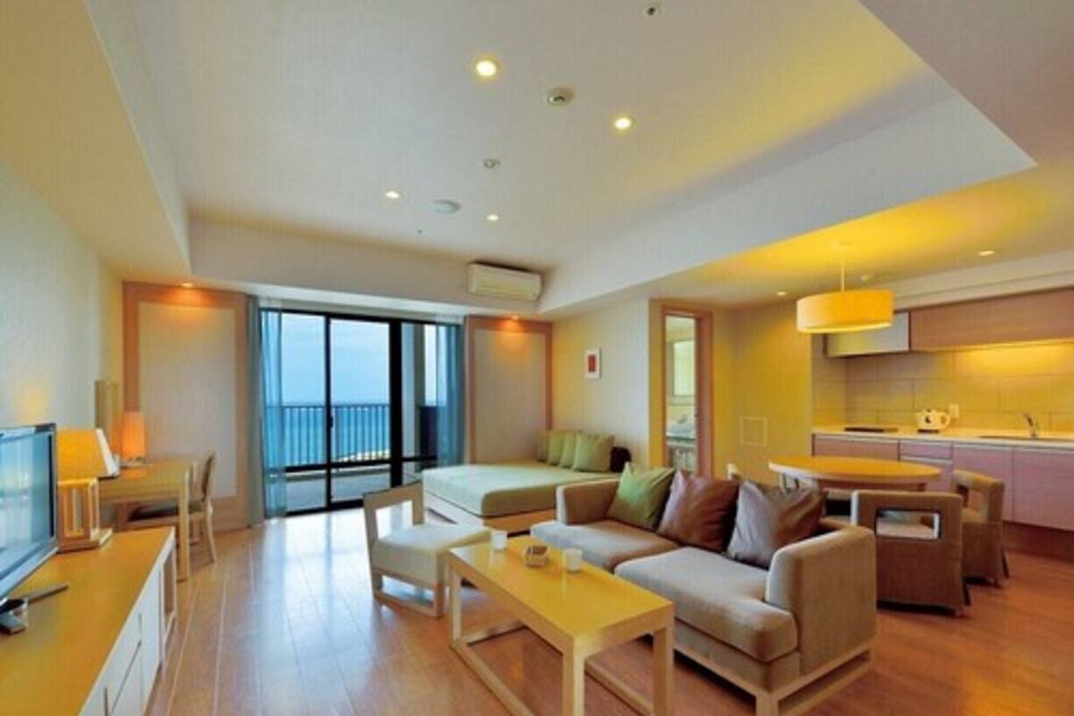 Una habitación de hotel moderna con balcón, sofá, comedor y cocina.