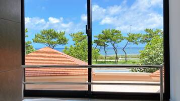 A bathroom with a large bathtub, a window with a view of trees and a building with a red roof.