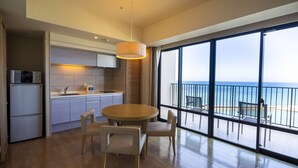 Una cocina moderna con una mesa redonda y sillas, vista al mar a través de amplios ventanales y un balcón con mobiliario exterior.