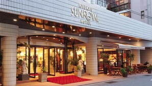 The Ryukyu Sunroyal Hotel exterior with a glass entrance, a red carpet, and outdoor seating. - Ryukyu Sun Royal Hotel (Naha)