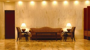 A lobby with a marble floor, a sofa, two armchairs, and two lamps. - Ryukyu Sun Royal Hotel (Naha)