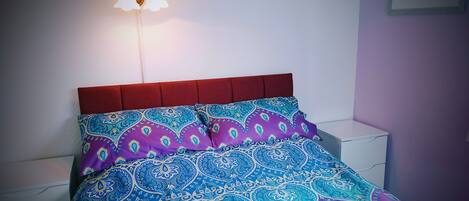 A bed with a patterned bedspread and a red headboard.
