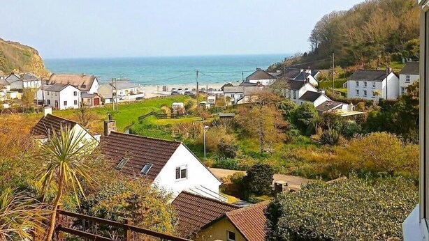 A coastal village with white houses, a view of the sea, and a green area in the foreground. - Gallen-treath Guest House (Helston)