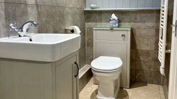 A bathroom with a white sink, a toilet, and a towel dispenser.