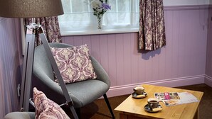 A cozy room with a grey armchair, a wooden coffee table with a magazine, and a lamp. - Sibton White Horse Inn (Saxmundham)