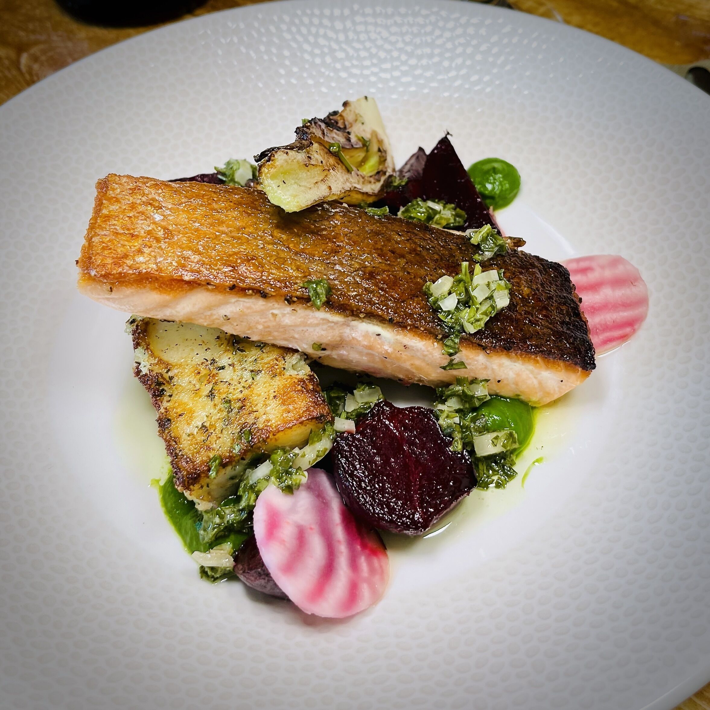 A plate of food with salmon, potatoes, and vegetables.