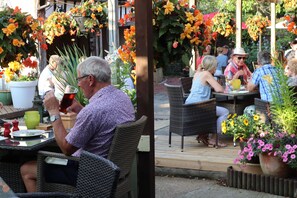 An outdoor seating area with wicker chairs and tables, surrounded by potted plants and hanging flower baskets. - Sibton White Horse Inn (Saxmundham)