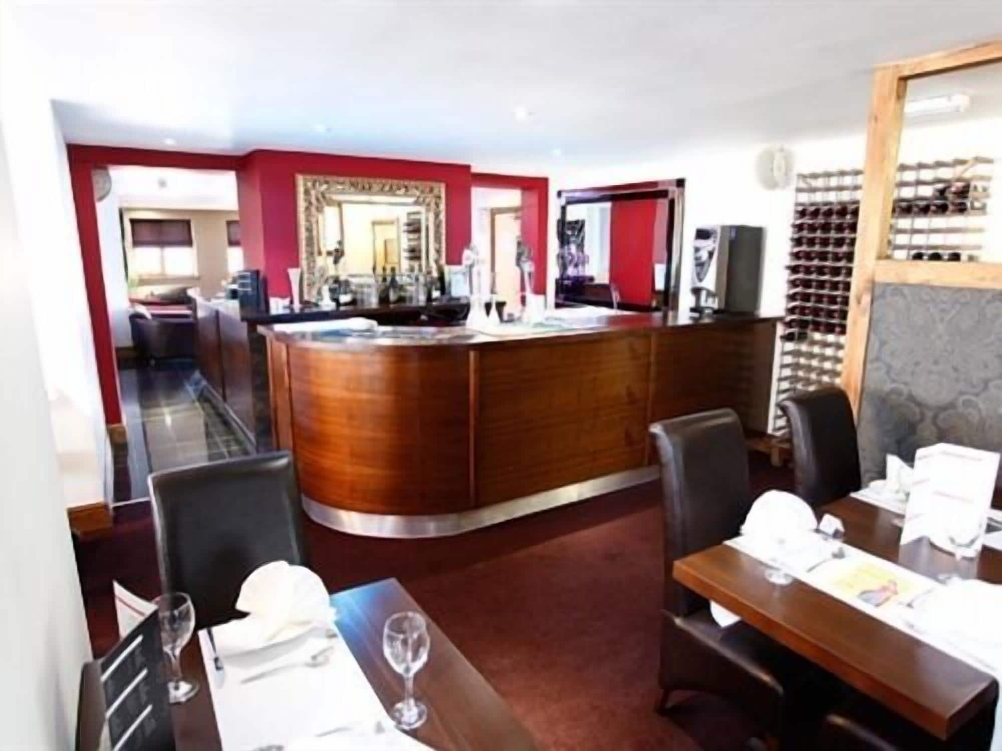 A restaurant with a wooden bar, dining tables, and chairs.