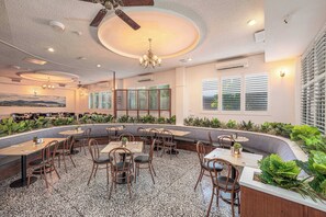 A restaurant with a curved seating area, multiple tables, and chairs. There are ceiling fans and recessed lighting. - Lees Hotel (Ingham)