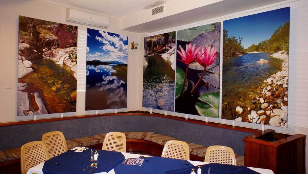 Uma sala de conferências com uma mesa comprida, quatro grandes pinturas de paisagens e cadeiras de vime.