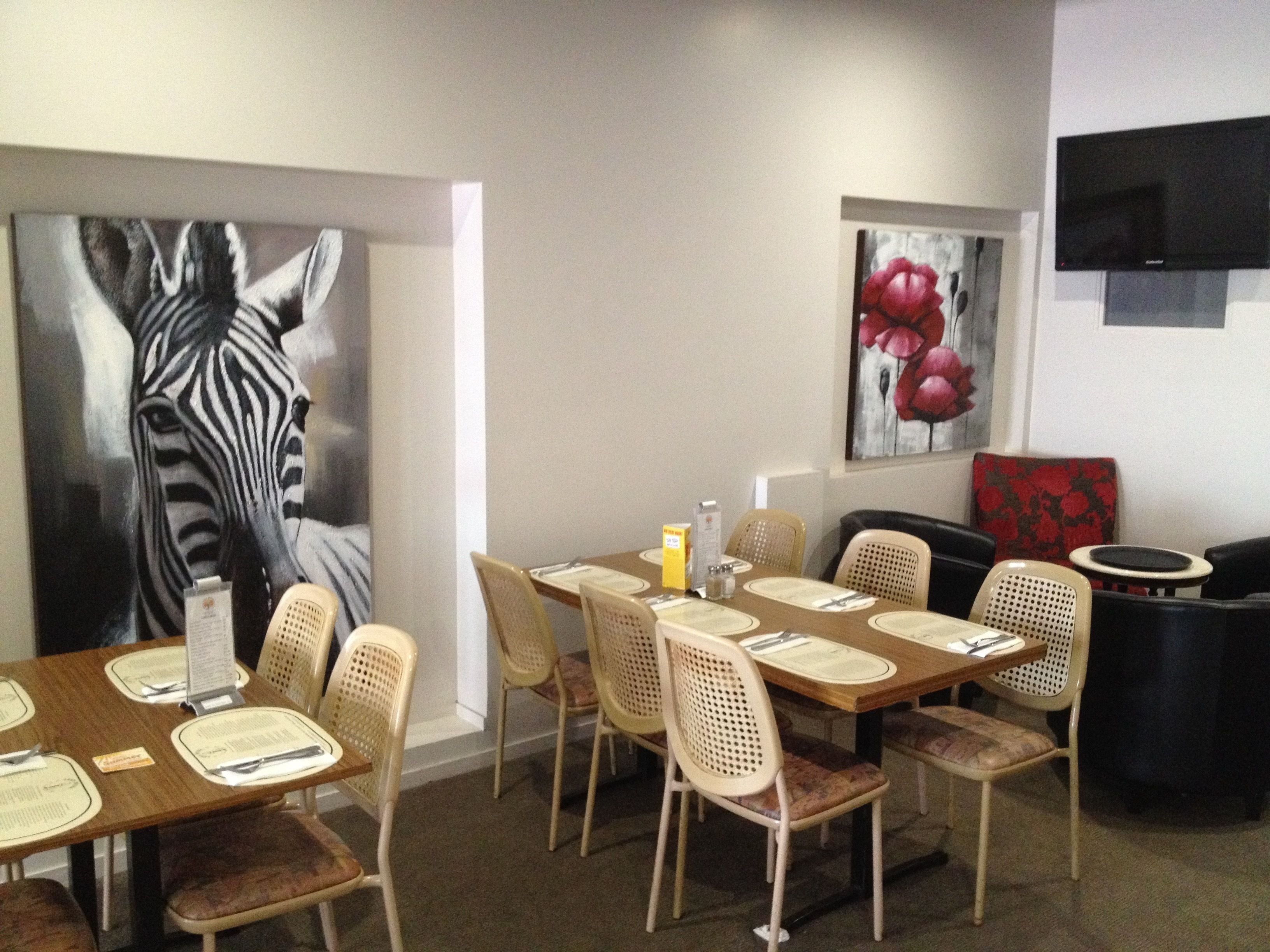 A dining area with a zebra mural, a flower painting, and a flat-screen TV.