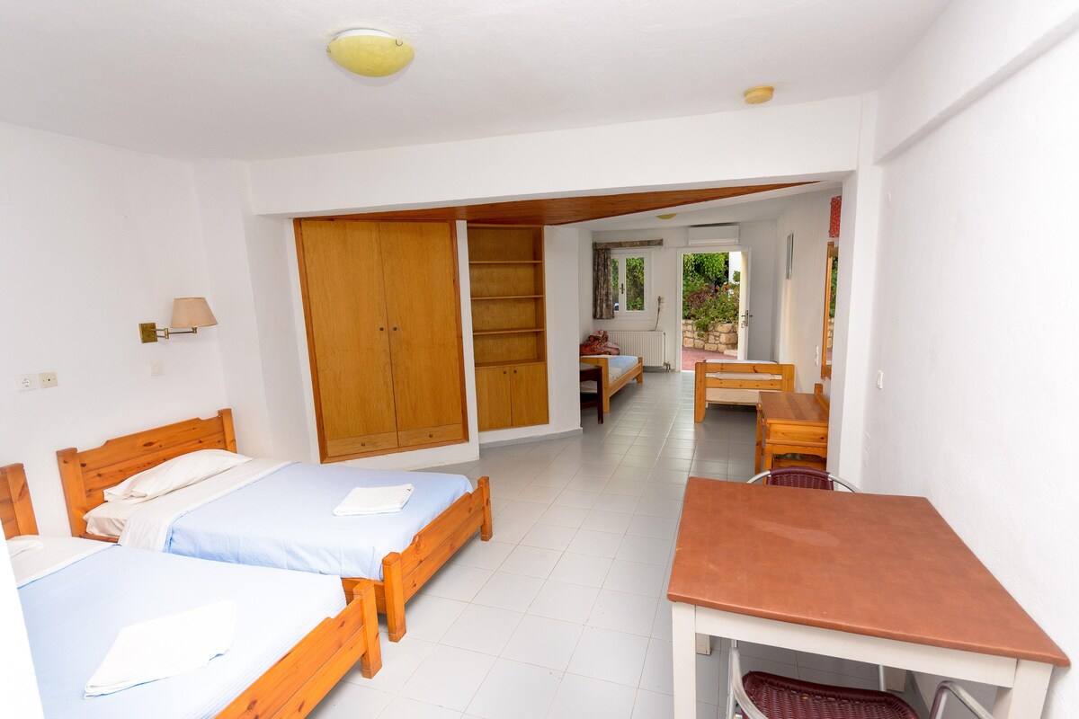 A room with two wooden beds, a wooden table, and a wardrobe.