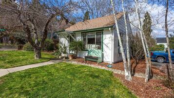 A small, single-story house with a front porch, a pathway leading to the entrance, and a blue car parked nearby.