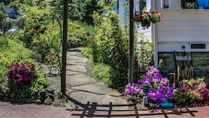 A garden pathway leading to a building with a pergola and hanging flower baskets. - Abigail’s Bed & Breakfast Inn (Ashland)