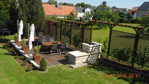 Une terrasse avec une table et des chaises, entourée d’une plateforme en bois et agrémentée d’une cheminée en pierre.