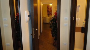 A hallway leading to a bedroom with a bed, a nightstand, and a potted plant. - B&B Il Campanile (Naples)