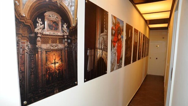 A hallway with a series of framed artworks on the wall, a tiled floor, and a door at the end. - B&B Il Campanile (Naples)