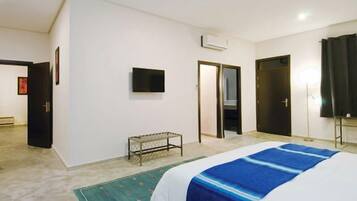 Una habitación de hotel con cama, televisor, banco y puerta.
