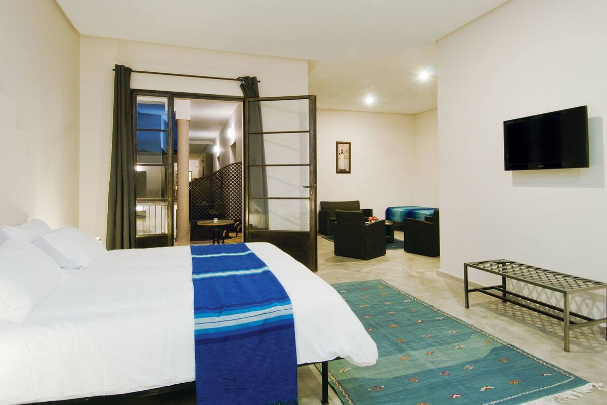 Habitación de hotel con cama, escritorio, silla, televisión y vista al exterior.