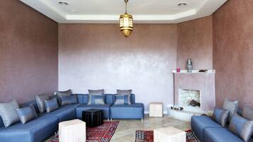 A spacious living room with a blue sofa set, a patterned rug, and a fireplace.