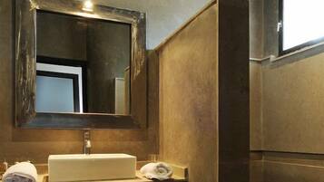 Un baño con un espejo grande, un lavabo y un perchero para toallas.