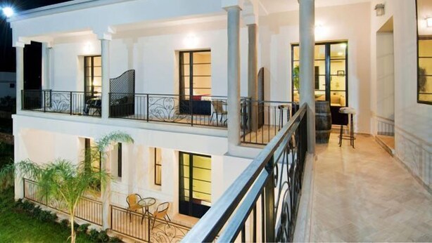 A multi-story building with balconies, outdoor seating, and a well-lit interior. - Villa Agapanthe (Fes)