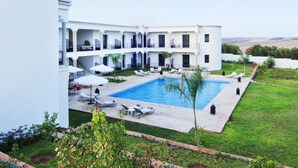 A hotel with a swimming pool, outdoor seating, and a view of the countryside. - Villa Agapanthe (Fes)