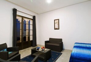 Un salon moderne avec un canapé, des fauteuils, une table basse et une grande fenêtre avec des rideaux.