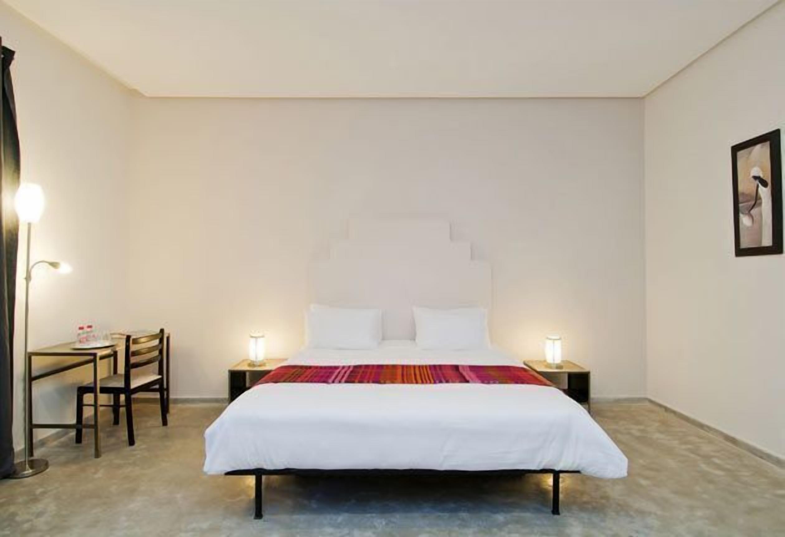 Una camera d'albergo con un letto, comodini, una scrivania e sedie.