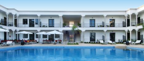 Una piscina al aire libre, sombrillas, sillones reclinables de piscina